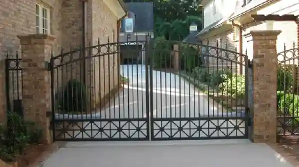 Custom ornamental double driveway gate installed between brick columns
