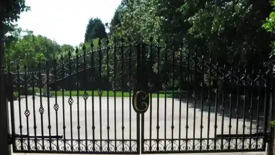 Black ornamental driveway gate with arched top, scrollwork and custom monogram