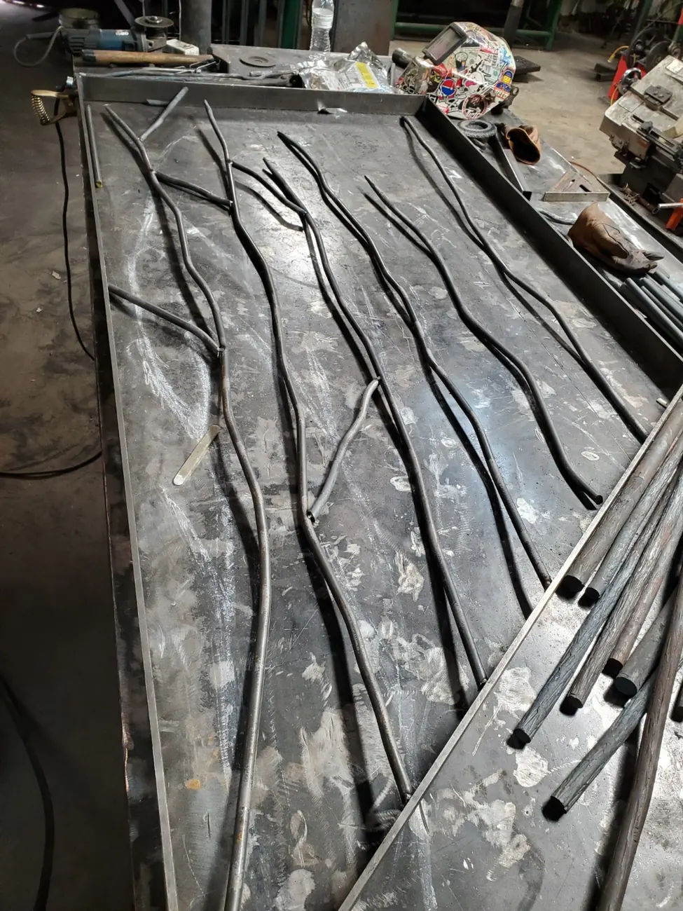 Custom steel tree-branch components being fitted by hand on a welding table